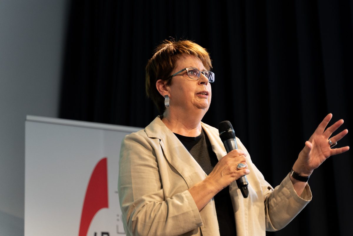 Person auf der Bühne spricht in ein Mikrofon.