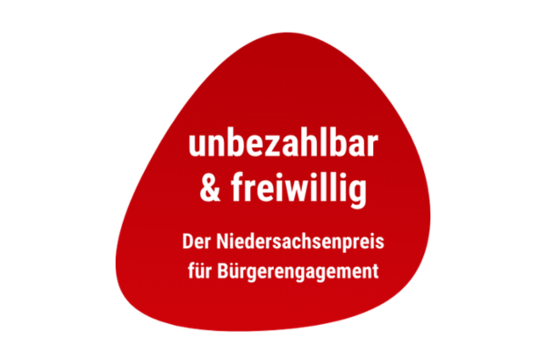 Rotes, abgerundetes Dreieck mit weißer Schrift 'unbezahlbar & freiwillig Der Niedersachsenpreis für Bürgerengagement'