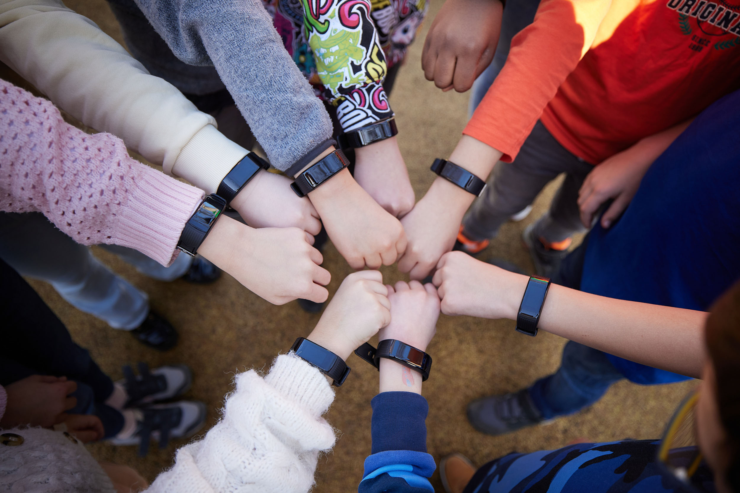 Viele Hände mit schwarzen Armbändern greifen in der Mitte eines Kreises zusammen.