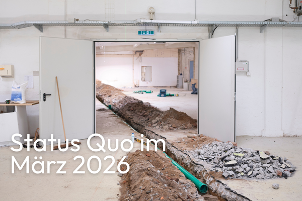 Aufgebrochener Hallenboden mit schmalem Graben voller Erde und grüner Rohre, dahinter offene Türen. Links unten steht großflächig der Text: 'Status Quo im März 2026'.